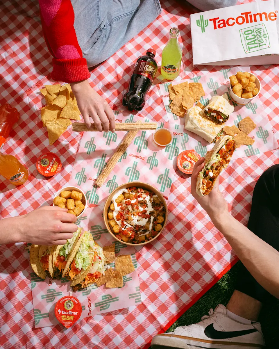 Overhead view of a TacoTime picnic on a red checkered blanket with tacos, burritos, churros, tater tots, and drinks shared among friends.
The appetite for Tex-Mex and Mexican