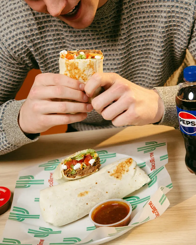 TacoTime hand-rolled burritos with fresh lettuce, tomato, and cheddar on a TacoTime restaurant table.